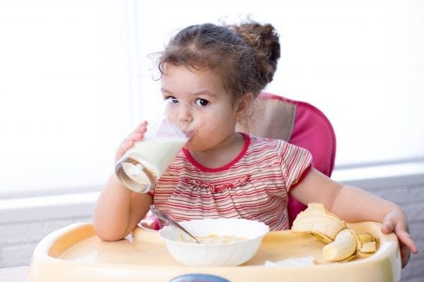 Young child drinking a glass of milk and benefiting from the Nursery Milk Scheme